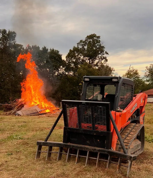 Heavy duty skid steer rake plow with brush guard attachment on jobsite